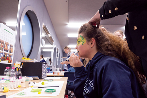 St Andrew's College student doing their makeup backstage at the Gough Family Theatre.