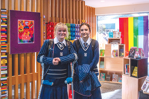 Two St Andrew's College students at The Green Library and Innovation Centre, viewing a special Pride Week book display.