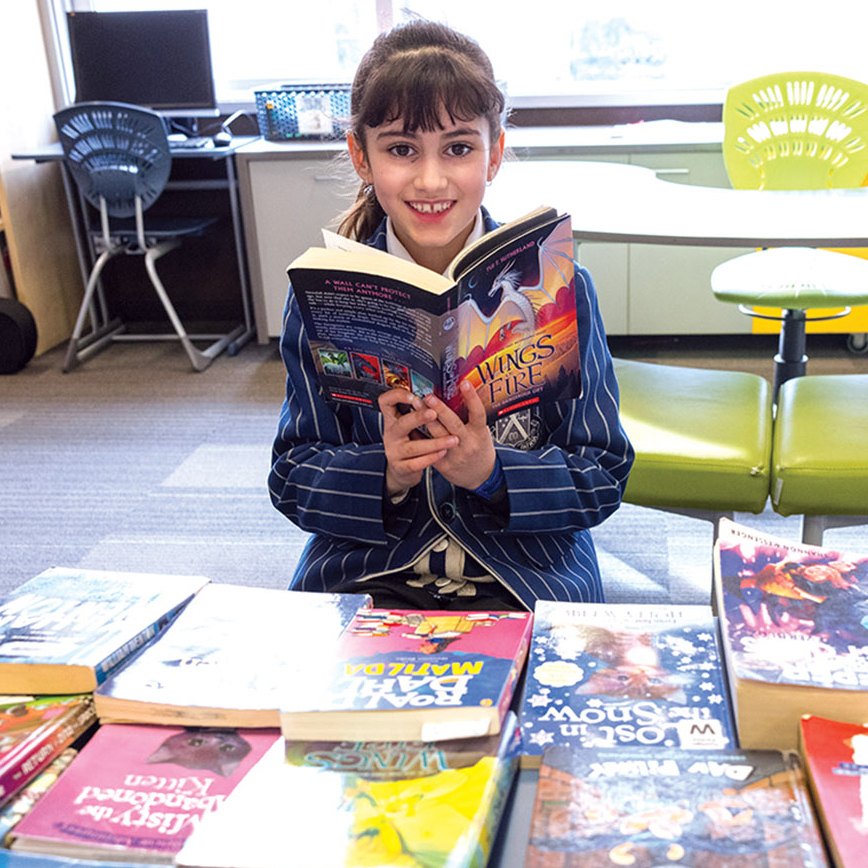 St Andrew's College student Reva Bartlett with many books.