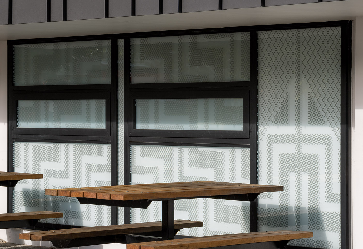 Ornamental latticework pattern in tukutuku style on the windows of St Andrew's College's new cafeteria, featuring the St Andrew's cross and traditional Māori elements.