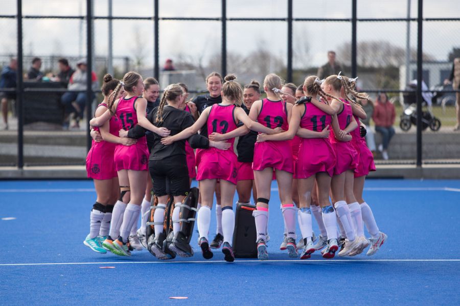 St Andrew's College female hockey players celebrating win on hockey pitch