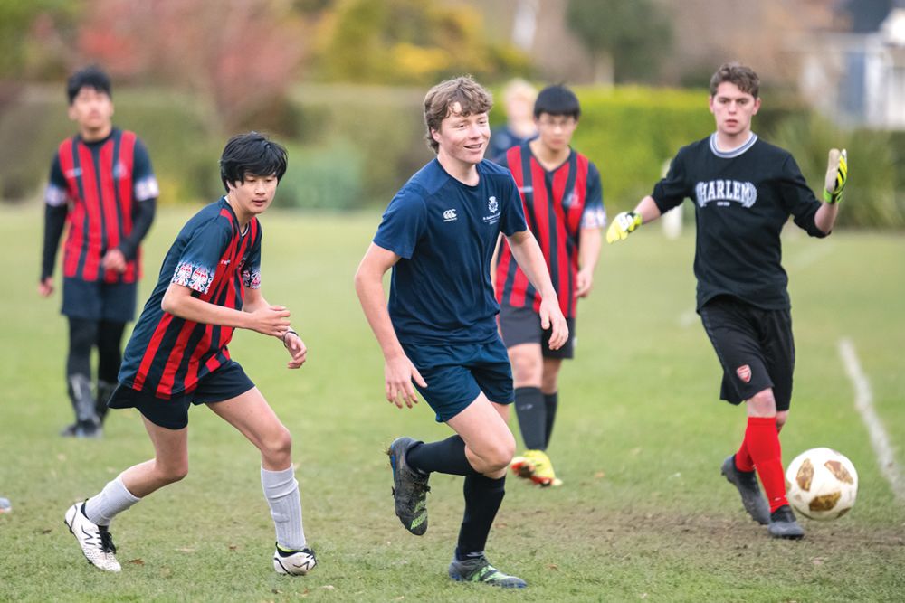 St Andrew's College student playing football.