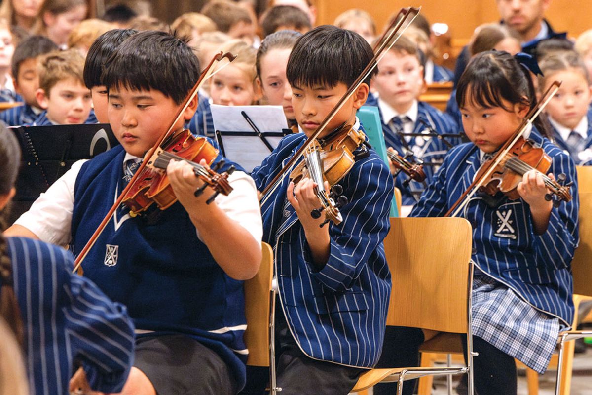 Three St Andrew's College students playing violin at a Preparatory School music concert.