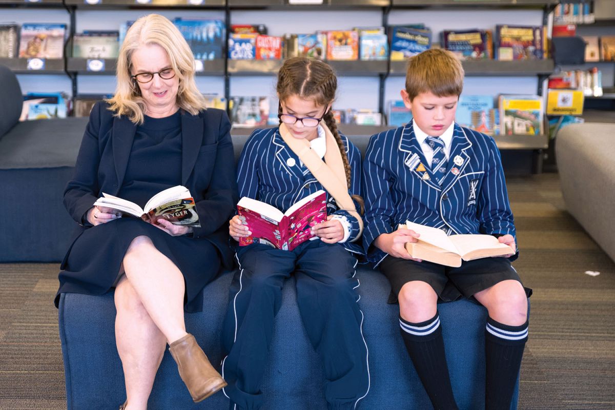 St Andrew's College Preparatory School Library Manager, Tracey Hull, reading books with Georgia Blyde and her brother Jack Blyde.