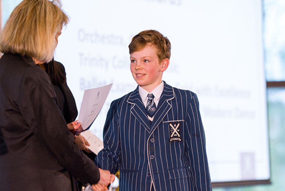 St Andrew's College student shaking the Rector's hand as he accepts an award at a Preparatory School assembly.