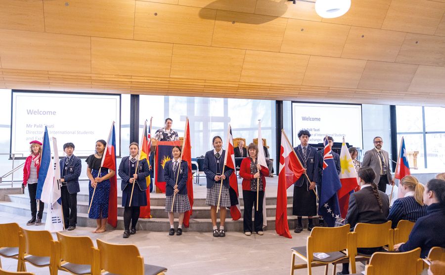 St Andrew's College students and teachers holding flags from different countries at the International Assembly in 2023.