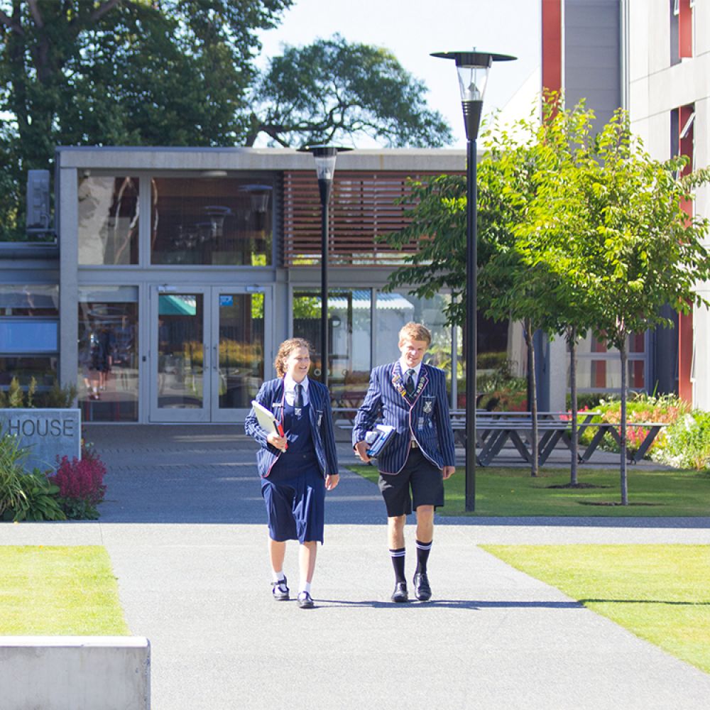 Two students walking outside boarding house.
