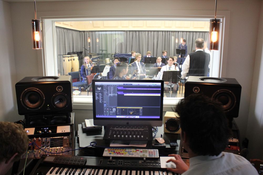 StAC music recording desk with students playing instruments in music room