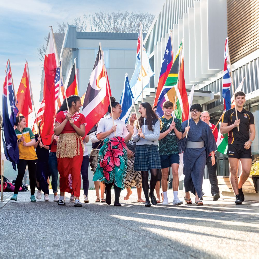 International students parade in national dress, with flags.