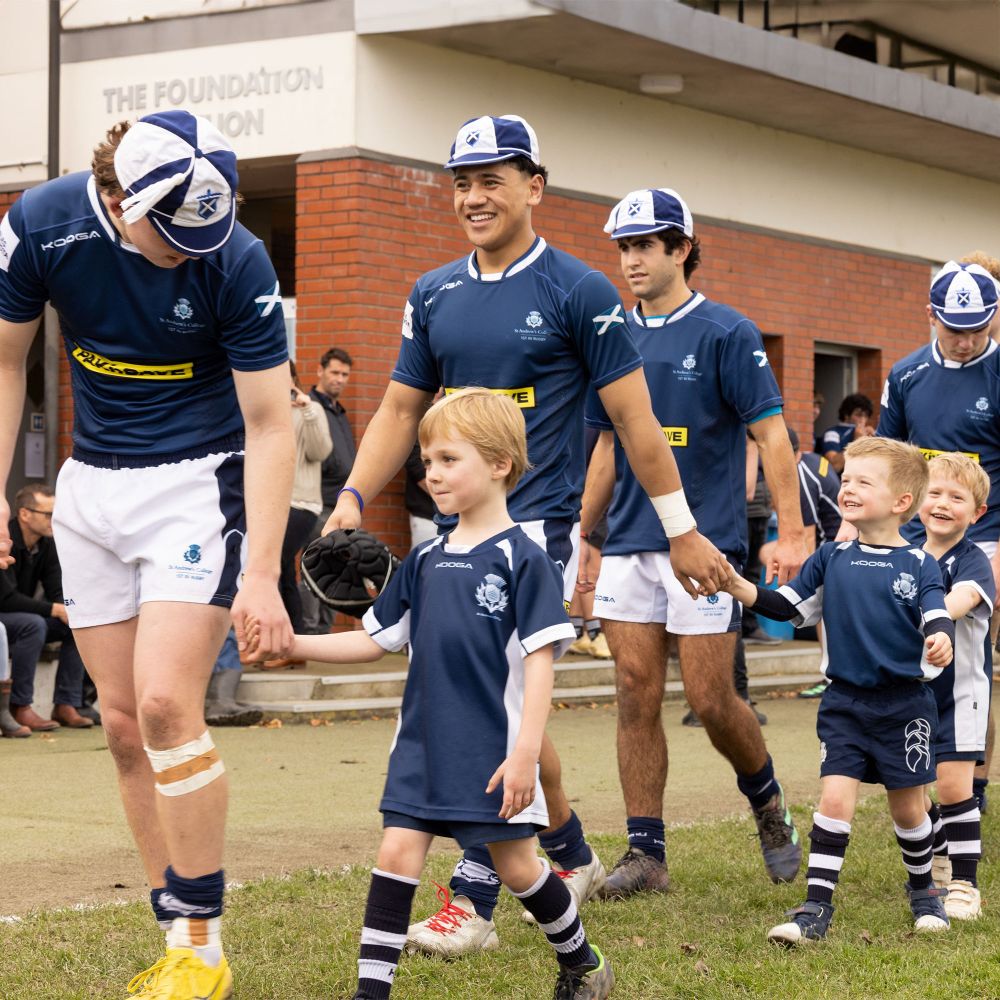 1st XV rugby team walking onto the pitch with 5 year olds.