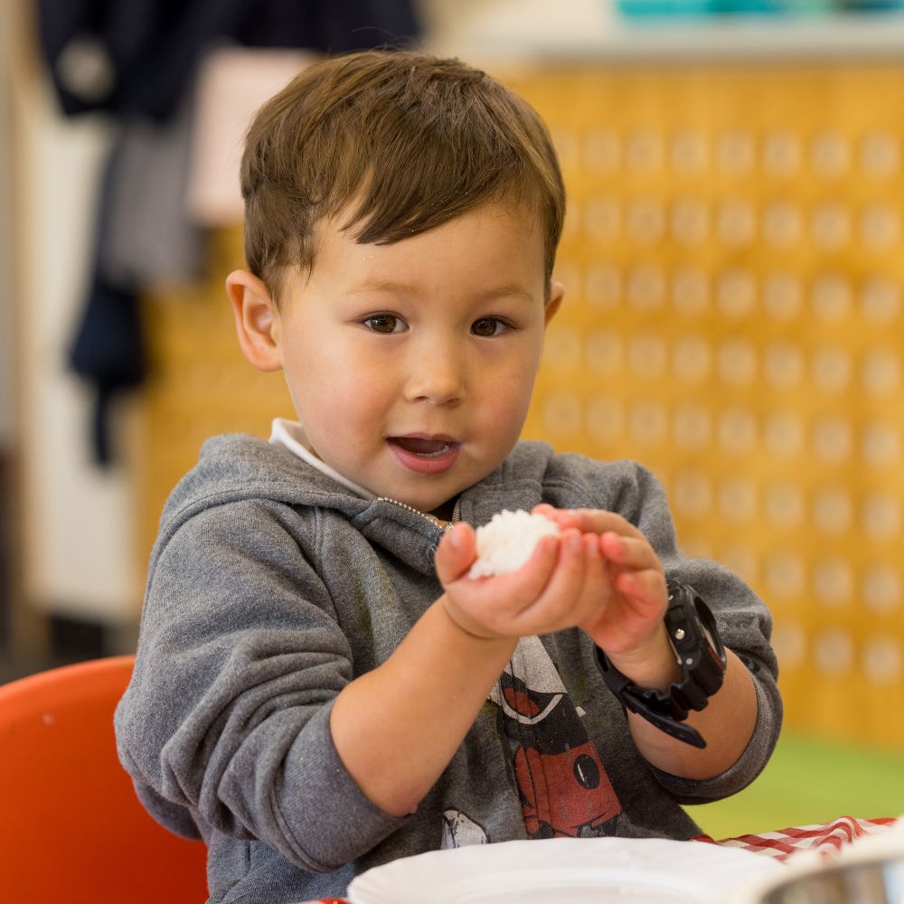 Child making a rice ball in the pre-school.
