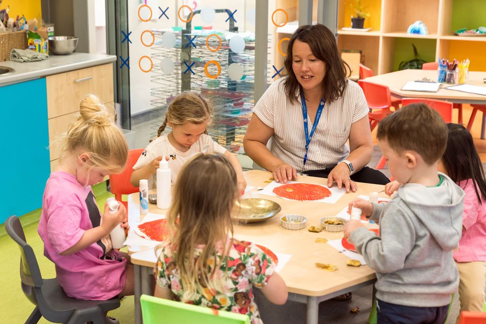 Head of St Andrew's College Pre-school, Mandy Jenkins and five children creating art.