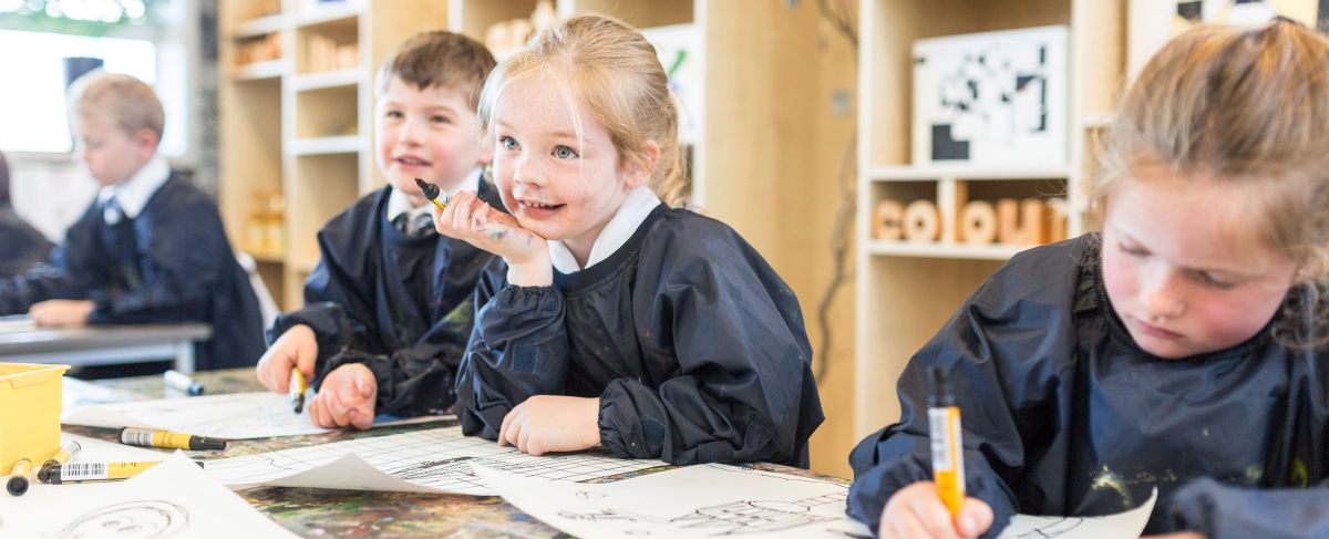Preparatory School students sat in an Art lesson wearing aprons