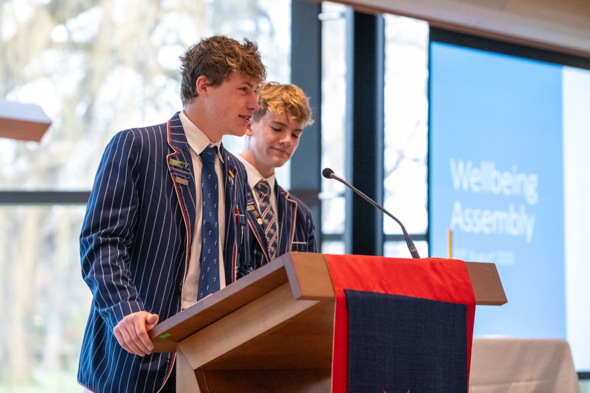 students speaking at the lectern in assembly